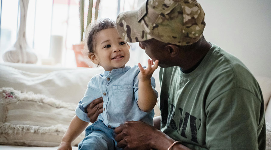 Cute baby playing with father soldier